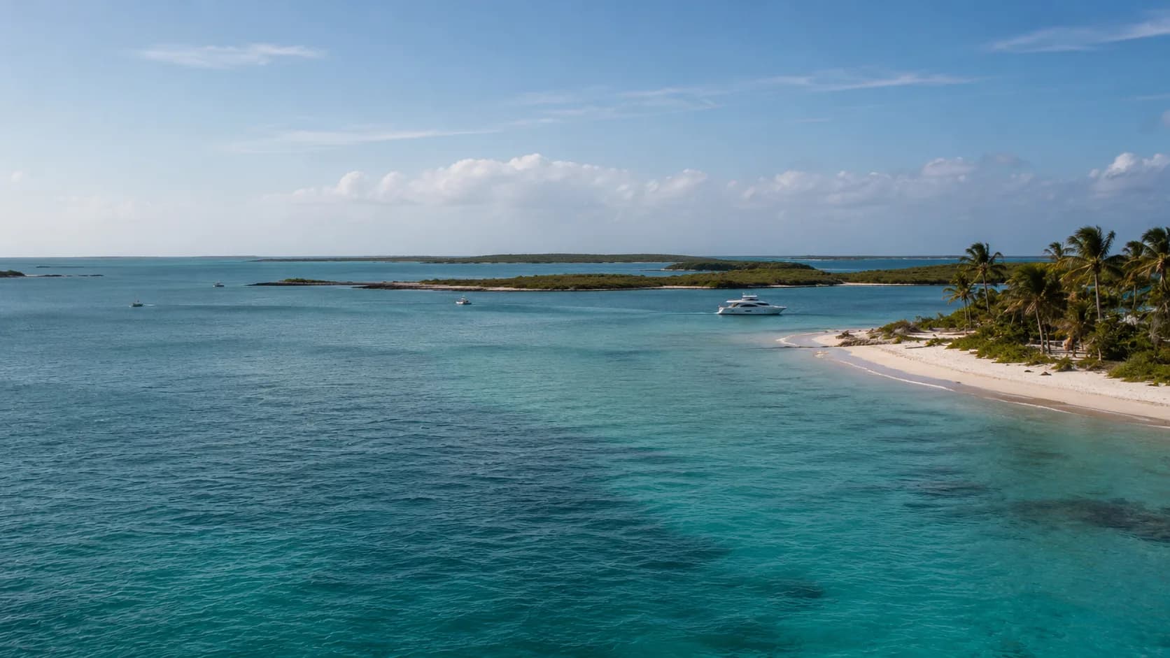 Motor yacht anchored off a white-sand cay in turquoise Bahamas water