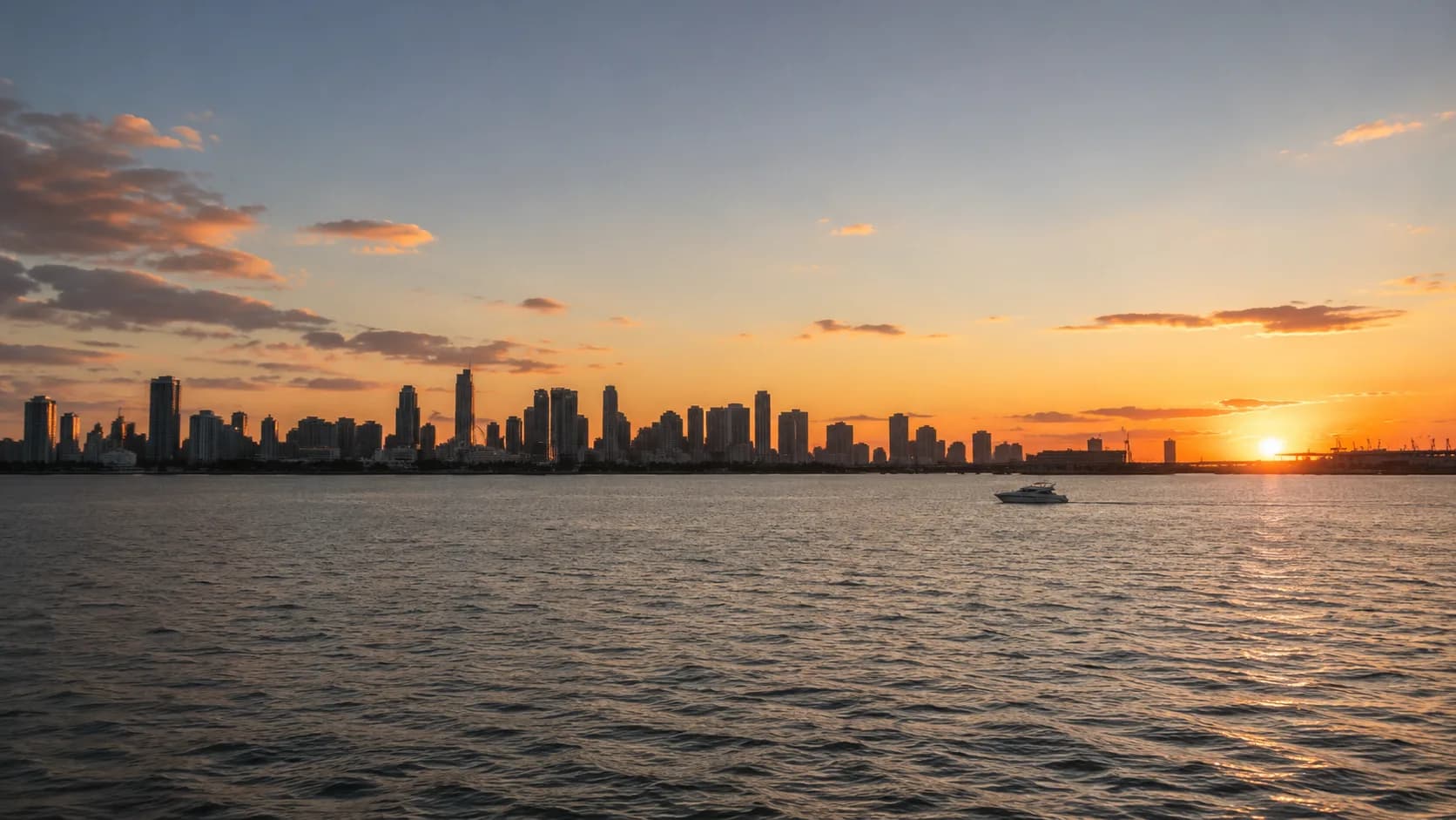 Motor yacht crossing Biscayne Bay at sunset with the Miami skyline behind